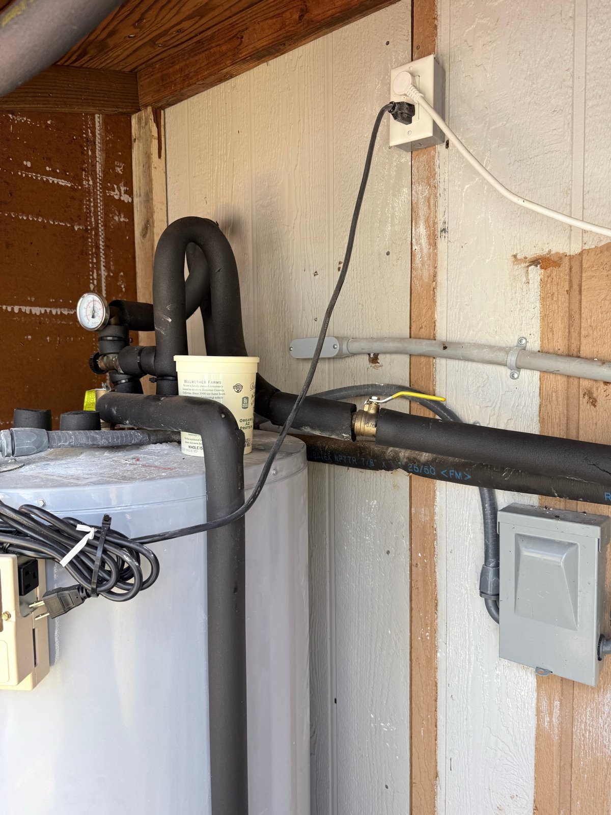 Documented electric water heater service with insulated piping, a pressure gauge, and a shut-off valve.